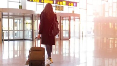 Woman walking through airport terminal with suitcase and backpack